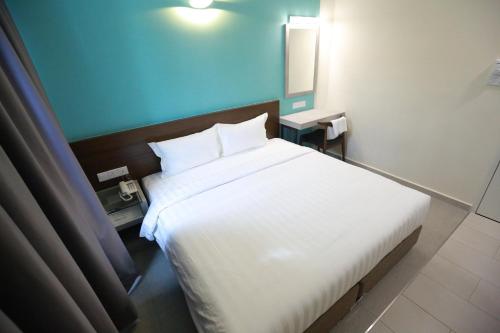 a bedroom with a white bed and a blue wall at Pantai Regal Boutique Hotel in Kuantan