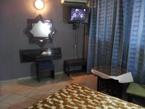 Hotel La Giralda في الناظور: غرفة نوم بسرير وتلفزيون وطاولة