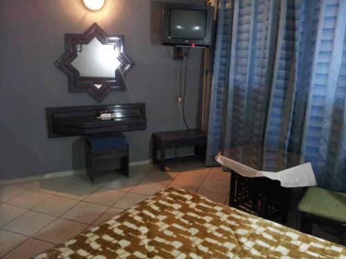 a room with a bed and a television and a table at Hotel La Giralda in Nador