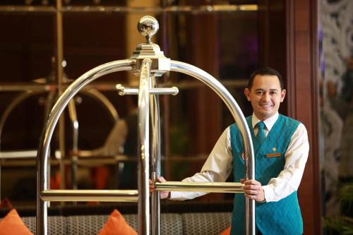 a man holding a cross in front of a room at Hotel Ciputra Cibubur managed by Swiss-Belhotel International in Cibubur