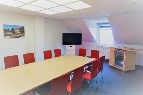 a conference room with a wooden table and red chairs at Hotel am Dom in Fulda