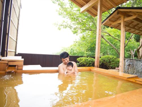 a man holding a baby in a swimming pool at Arima Onsen Motoyu Ryuusenkaku in Kobe