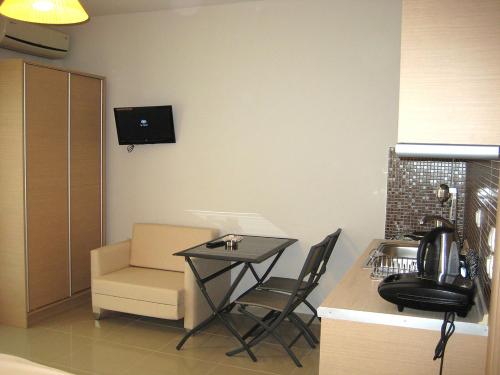 a kitchen with a table and a chair and a television at TETYK Keramoti Hotel Apartments in Keramotí