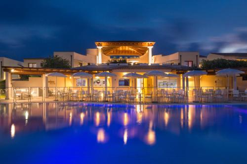 a resort with chairs and umbrellas at night at Grande Baia Resort & Spa in San Teodoro