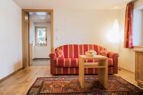 a living room with a red couch and a table at Caroline's Appartement in Au im Bregenzerwald