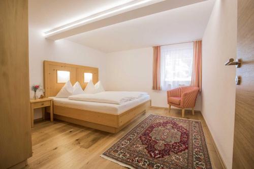 a bedroom with a bed and a chair and a window at Caroline's Appartement in Au im Bregenzerwald