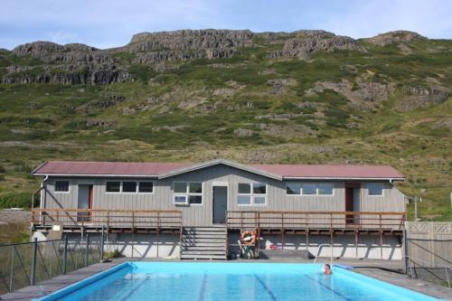 a house with a swimming pool in front of a house at Hótel Laugarhóll with natural hot spring in Laugarholl