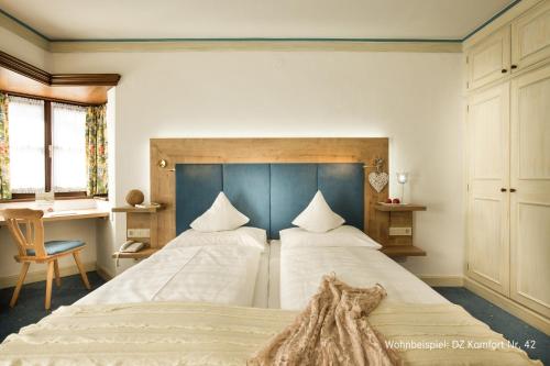 a bedroom with two beds and a desk at Johannesbad Hotel St. Georg in Bad Hofgastein