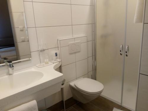 a white bathroom with a toilet and a sink at Hotel Restaurant zum Schwan in Schwanberg