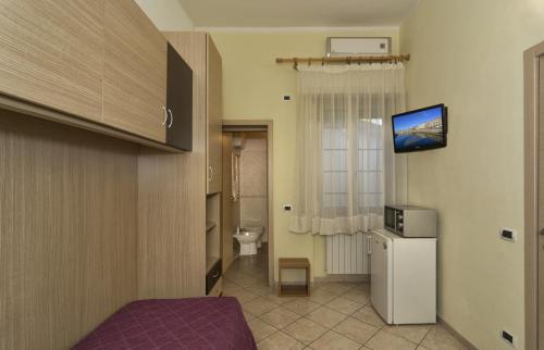 Habitación con baño con nevera y TV. en Affittacamere Elisa, en Pisa