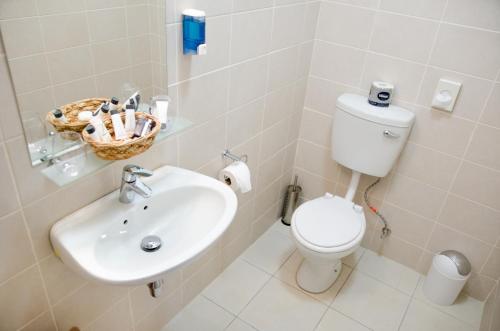 a white bathroom with a toilet and a sink at Hotel Deutsches Haus Swakopmund in Swakopmund