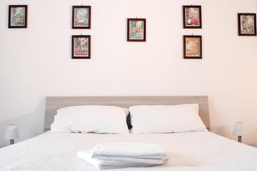 ナポリにあるCasa Vacanze Umberto Iの白いベッド1台、壁に4枚の写真が飾られたベッドルーム1室
