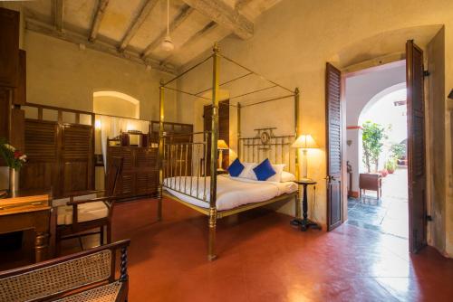 a bedroom with a canopy bed with blue pillows at Dune de L'orient in Pondicherry