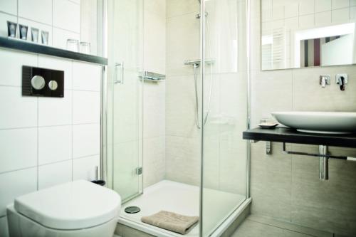 a bathroom with a shower and a toilet and a sink at City Hotel Bosse in Bad Oeynhausen