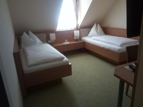 two beds in a small room with a window at Hotel Restaurant zum Schwan in Schwanberg