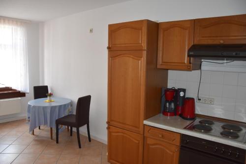 eine Küche mit Holzschränken und einem Tisch mit einem kleinen Tisch in der Unterkunft Ferienwohnungen Familie Jäschke in Görlitz