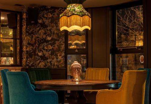 a table in a room with chairs and a chandelier at House Belfast Hotel in Belfast
