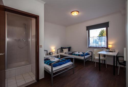 ノイブランデンブルクにあるPension ,,Vier Tore''のベッド2台とシャワーが備わる小さな客室です。