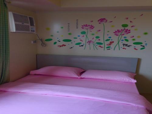 1 dormitorio con 1 cama con sábanas rosas y flores en la pared en Avida Towers Condotel, en Davao City