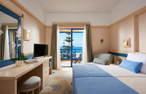 a hotel room with a bed and a desk with a television at Aldemar Olympian Village in Olympia