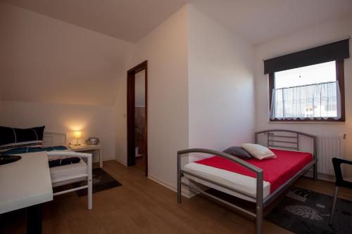 a bedroom with two beds and a table and a window at Pension ,,Vier Tore'' in Neubrandenburg