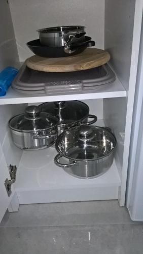 three pots and pans on a shelf in a kitchen at Széchenyi Apartman Miskolc belvárosban in Miskolc