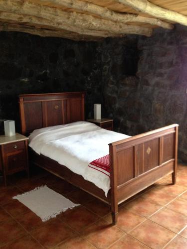 a bedroom with a wooden bed and two night stands at Casa Da Lava in São Roque do Pico