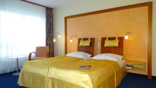 a hotel room with a large bed with a yellow bedspread at Hotel Ascot Bristol in Potsdam