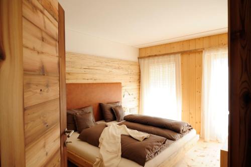 a bedroom with a bed and a wooden wall at Hotel Naturoase Schwemmerhof in Ultimo