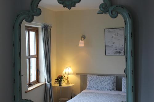 Clifden Bay Lodge في كليفدين: غرفة نوم مع سرير مع مرآة كبيرة