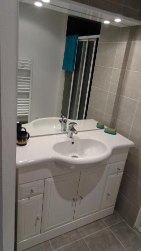 een badkamer met een witte wastafel en een spiegel bij Appart T4 Luchon plein centre in Luchon