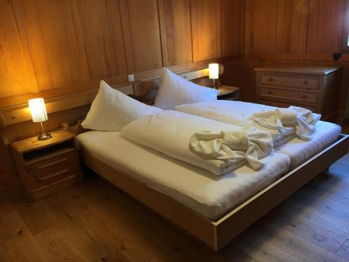 a bed with white sheets and a teddy bear on it at Alpenstern in Gaschurn