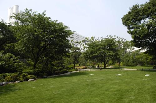 a park with green grass and trees and a building at Grand Prince Hotel Shin Takanawa in Tokyo