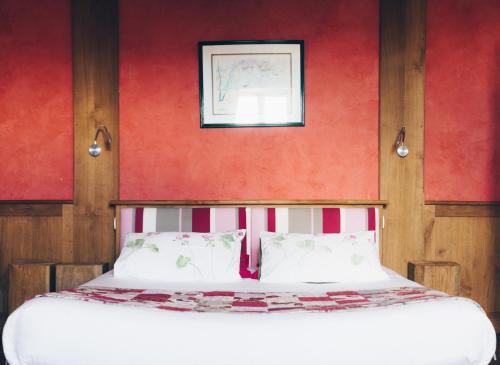 - une chambre dotée d'un lit avec un mur rouge dans l'établissement Chambres d'hôtes Le Clos d'Enhaut, à Dinard