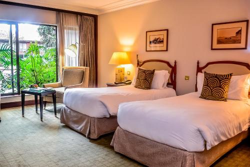 a hotel room with two beds and a window at Fairmont The Norfolk in Nairobi
