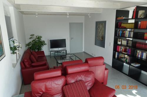 a living room with red chairs and a television at Ferienwohnung Himmlingen in Aalen