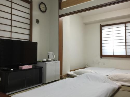 a bedroom with two beds and a flat screen tv at Shin Okubo Sekitei in Tokyo