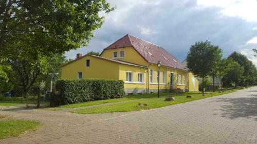 ein gelbes Haus am Straßenrand in der Unterkunft Sommergutshaus Ferienwohnungen in Netzeband