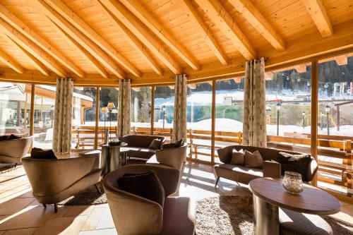 a lobby with chairs and tables and windows at Wellness-Sporthotel Ratschings in Racines