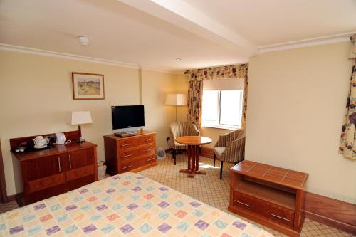 a hotel room with a bed and a desk and a television at Expanse Hotel in Bridlington