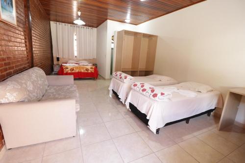 a room with two beds and a couch in it at Hotel Rural Vale das Nascentes in Salesópolis