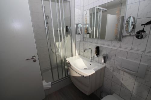 a white bathroom with a sink and a shower at Hotel Engel in Kappel-Grafenhausen