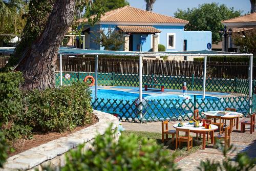 a pool with tables and chairs next to a house at Aldemar Olympian Village in Olympia