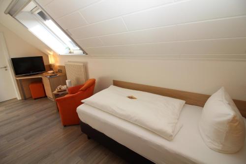 a bedroom with a bed and a chair and a television at Hotel Engel in Kappel-Grafenhausen