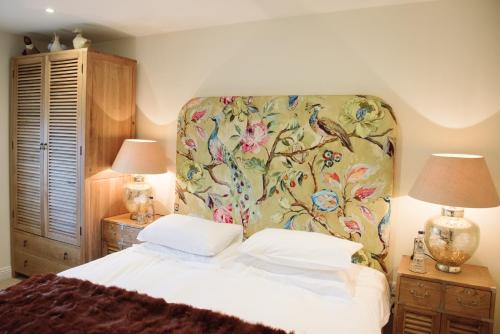 a bedroom with a bed with a floral headboard and two lamps at The Turtley Corn Mill in South Brent
