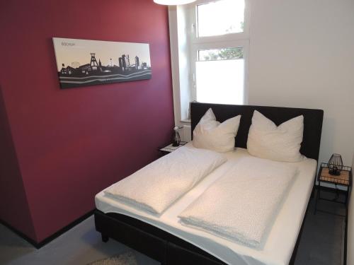 a bedroom with a white bed with a red wall at Zentrales Apartment in Gelsenkirchen in Gelsenkirchen