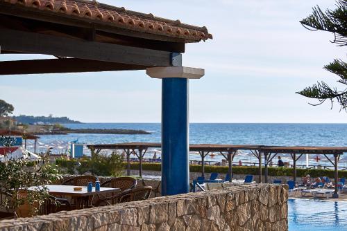 a view of a beach with tables and chairs and the ocean at Aldemar Olympian Village in Olympia