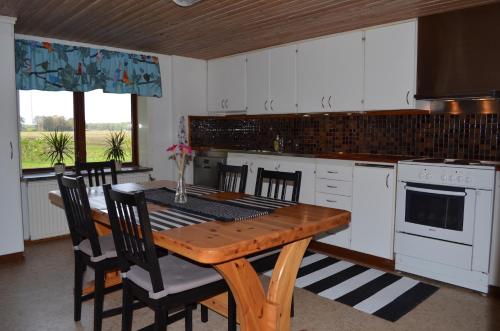 una cocina con mesa de madera y una cocina con armarios blancos. en Smedsgården, en Höganäs