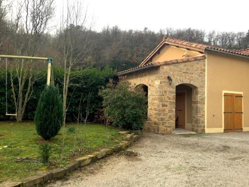 a stone house with a garage in a yard at Le Chat Blanc Gîte in Versols-et-Lapeyre