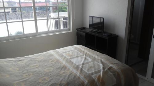 a bedroom with a bed and a flat screen tv at Casa privada para descanso, se renta para 8 personas completa Y tambien por habitacion con baño privado para 2 o 4 personas compartiendo areas comunes in Cuernavaca